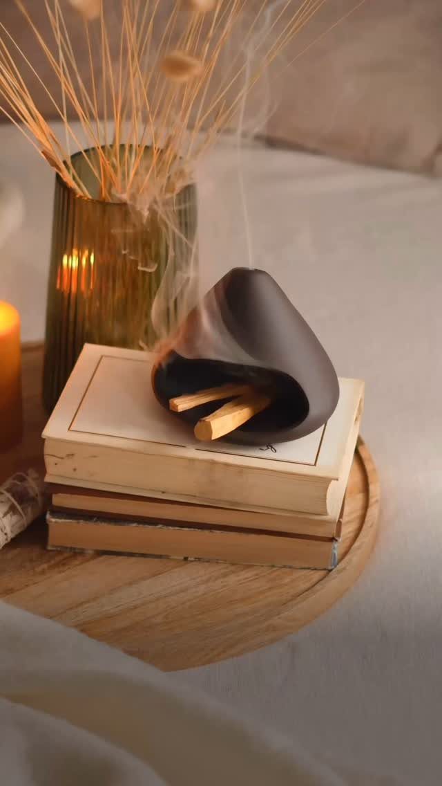 Incense burner with smoking sticks on a stack of books and wooden tray