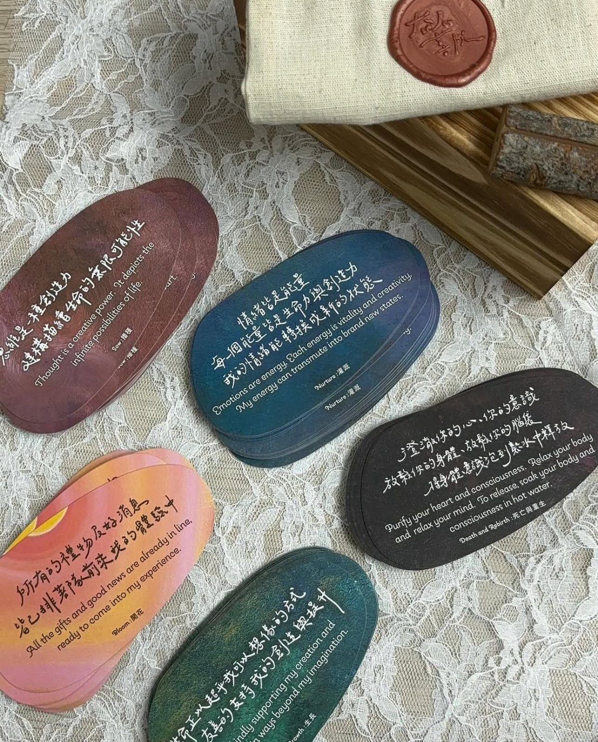 Five colorful inscribed stones on a white lace cloth next to a pouch.