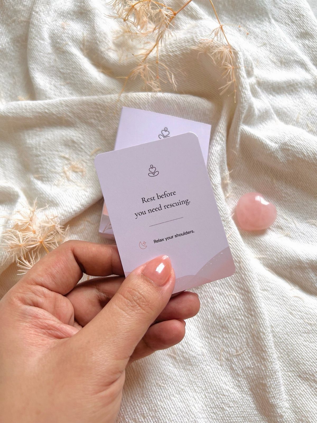 Hand holding a mindfulness card with a quote on white textured fabric.