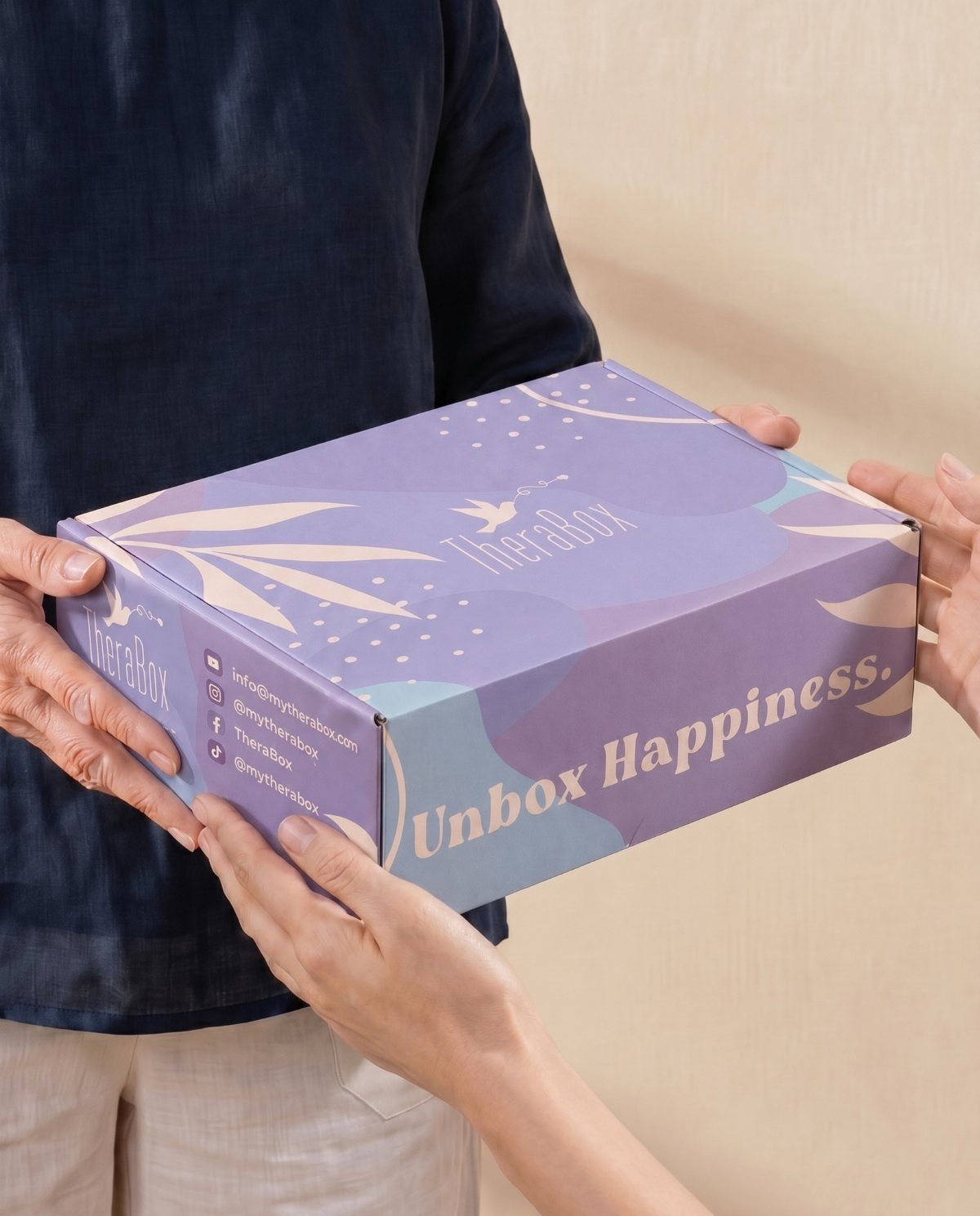 Hands holding a purple TheraBox subscription box with the words Unbox Happiness.