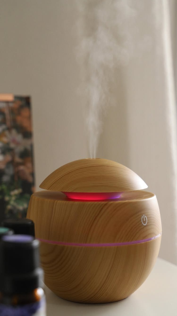 Wooden spherical aromatherapy diffuser emitting white mist with a glowing pink light ring.
