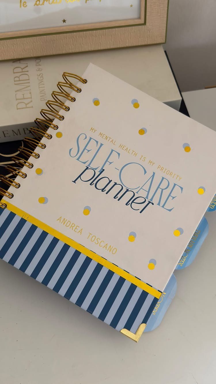 Self-care planner with gold spiral binding and blue and yellow decorative accents.