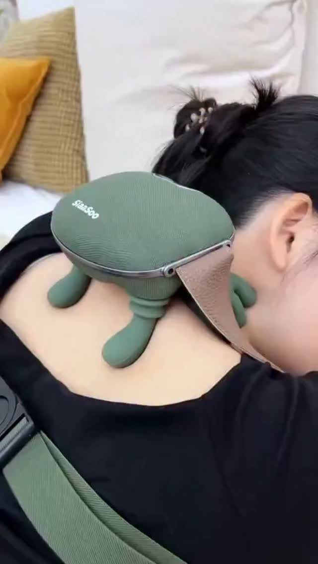 Green electric neck and shoulder massager being used on a person's upper back.