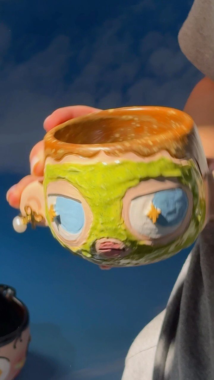 Ceramic mug shaped like a face wearing a green skincare face mask.