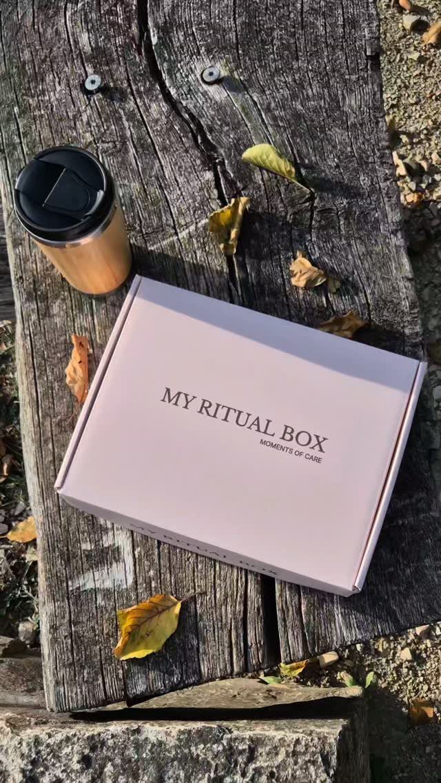 Light pink ritual gift box and bamboo travel mug on weathered wooden planks.