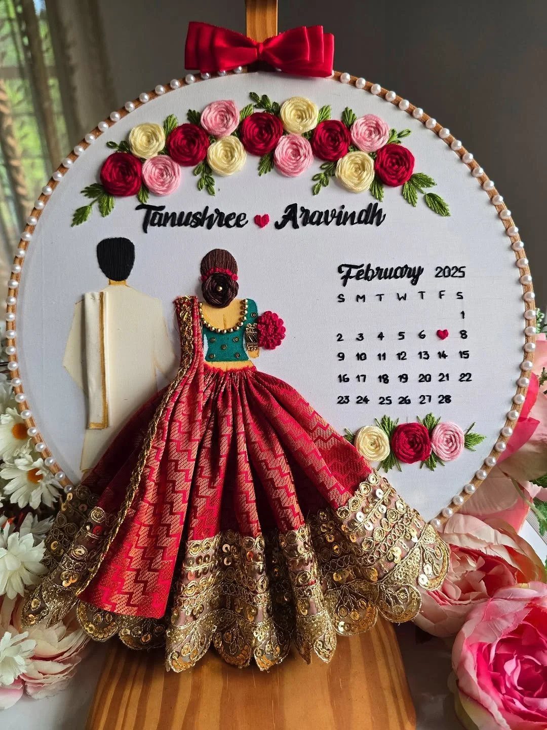 Embroidery hoop art showing a couple in traditional Indian wedding clothes with calendar