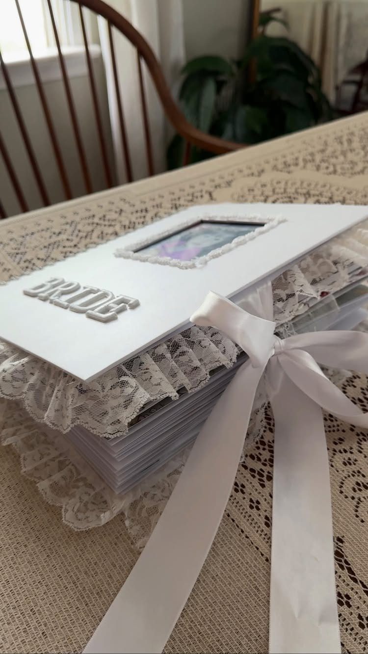 White handmade bridal scrapbook with lace trim, satin ribbon, and 'BRIDE' lettering.