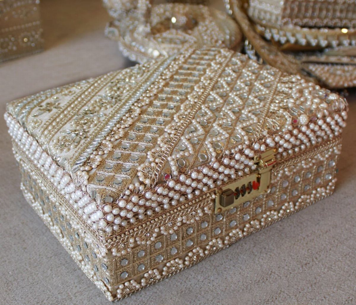 Ornate jewelry box decorated with white pearls, gold embroidery, and mirrored tiles.