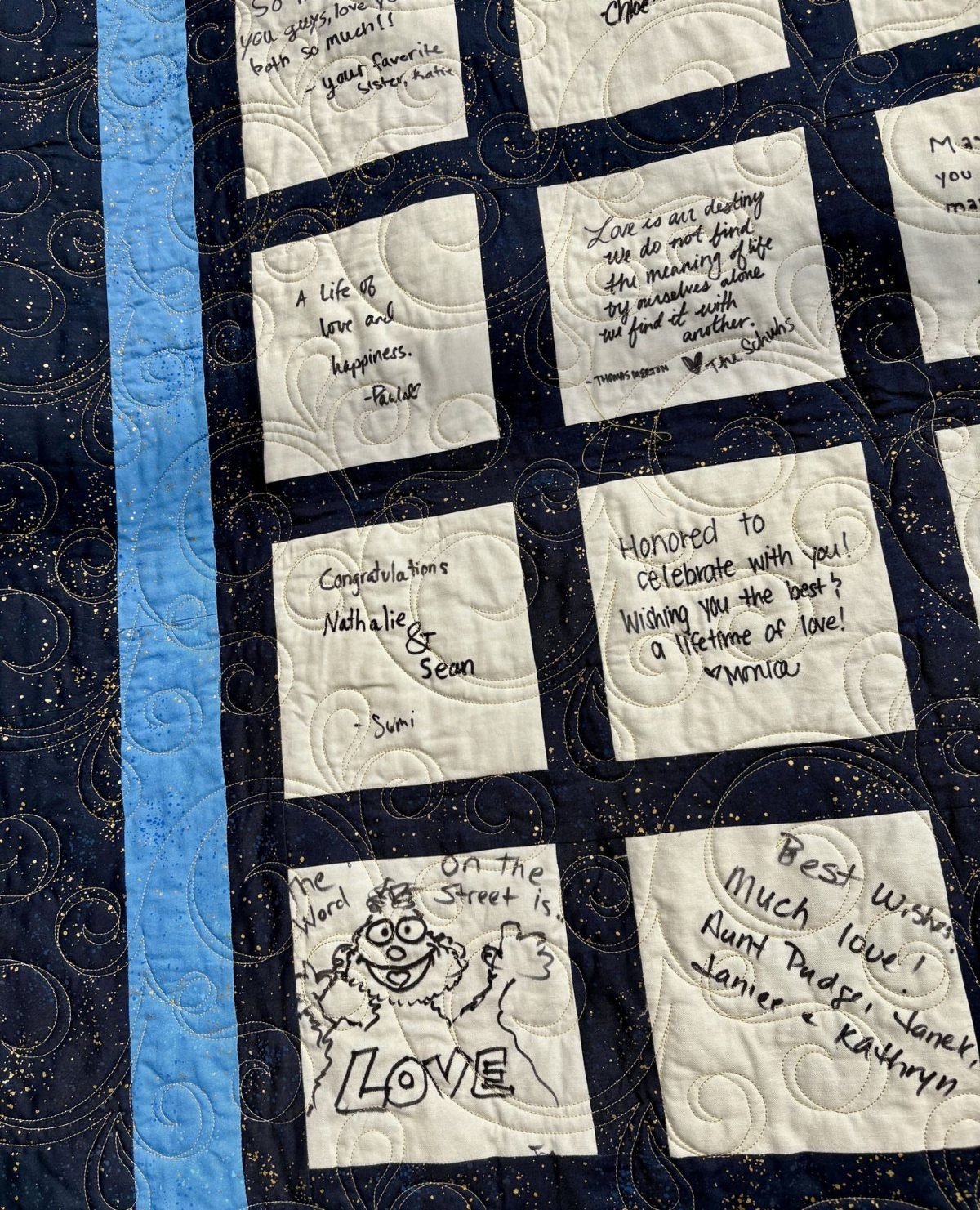 Quilted navy and white blanket with handwritten wedding messages on square fabric patches.
