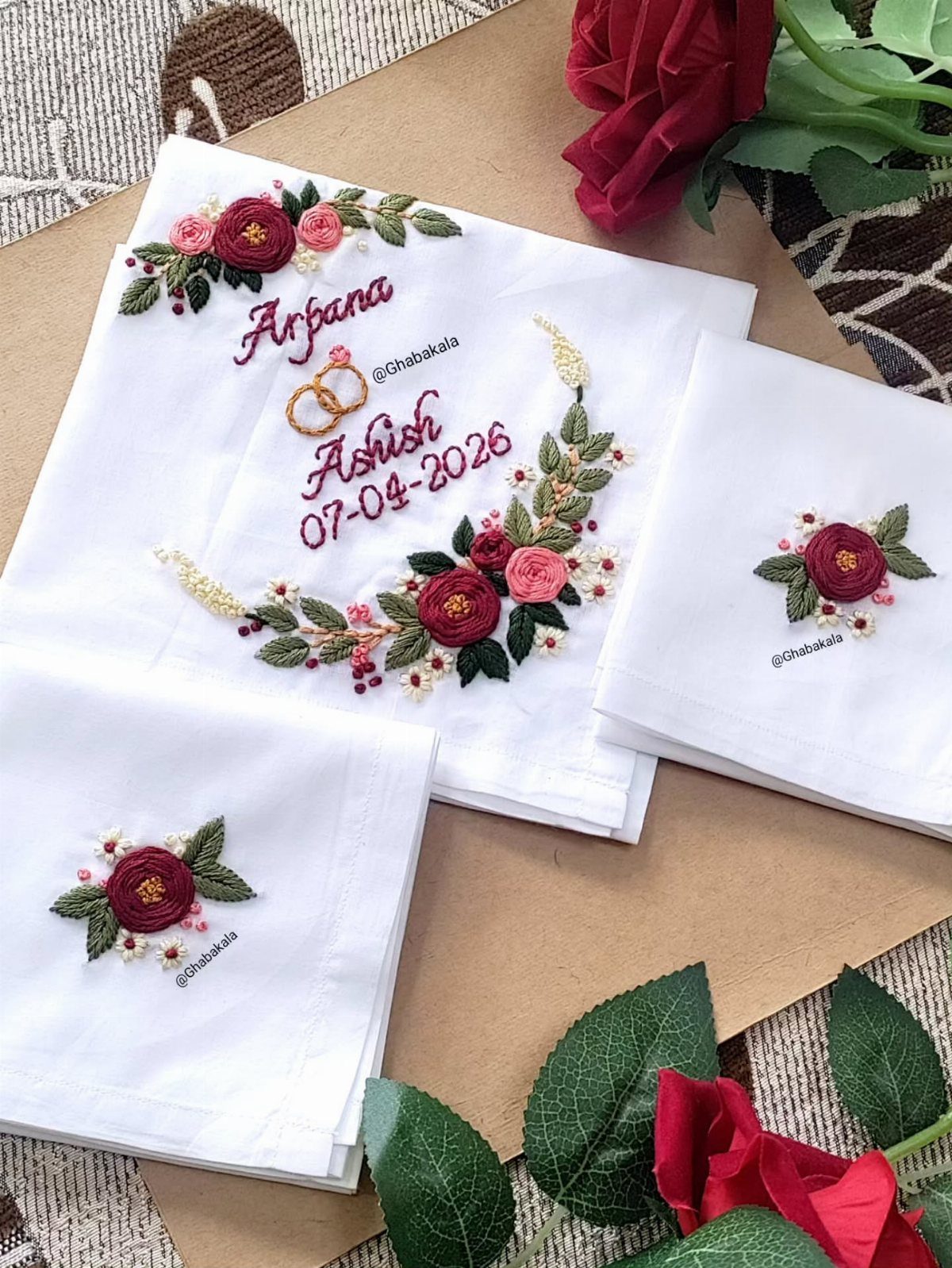 Embroidered white wedding handkerchiefs with red floral designs and personalized names and date.