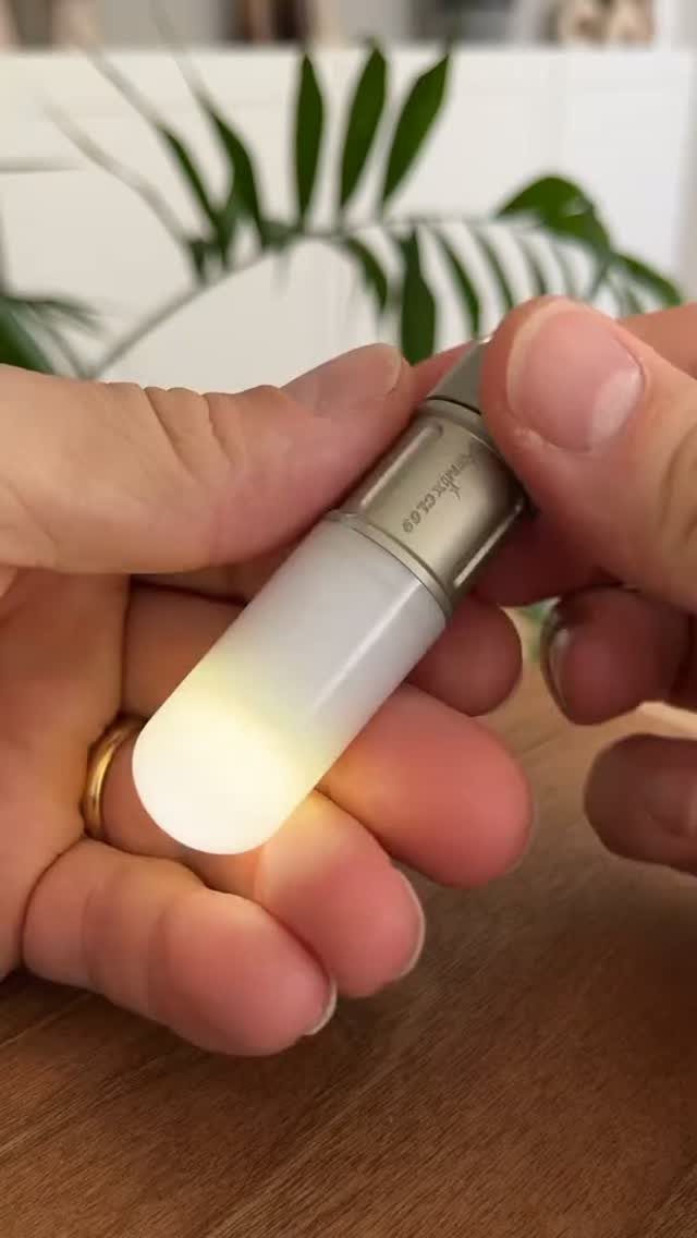 Small metal flashlight with a glowing white tip held by two hands.