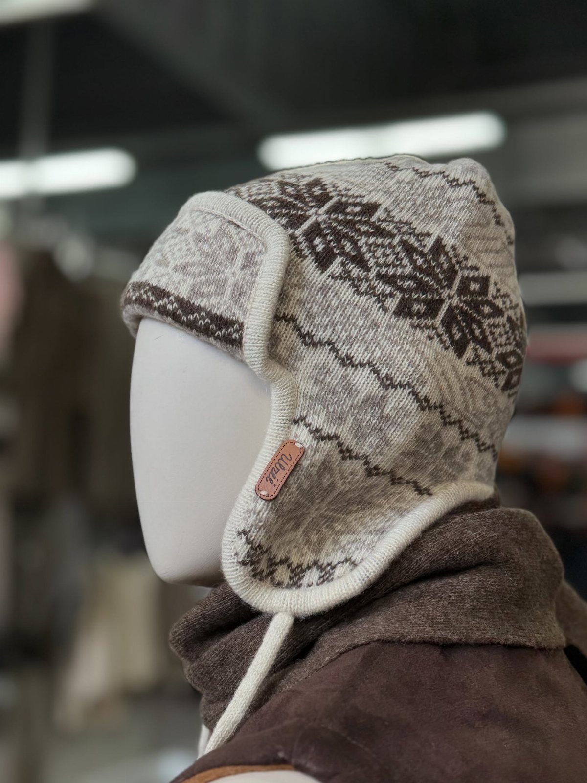 Brown and cream patterned knit trapper hat and scarf on a mannequin head