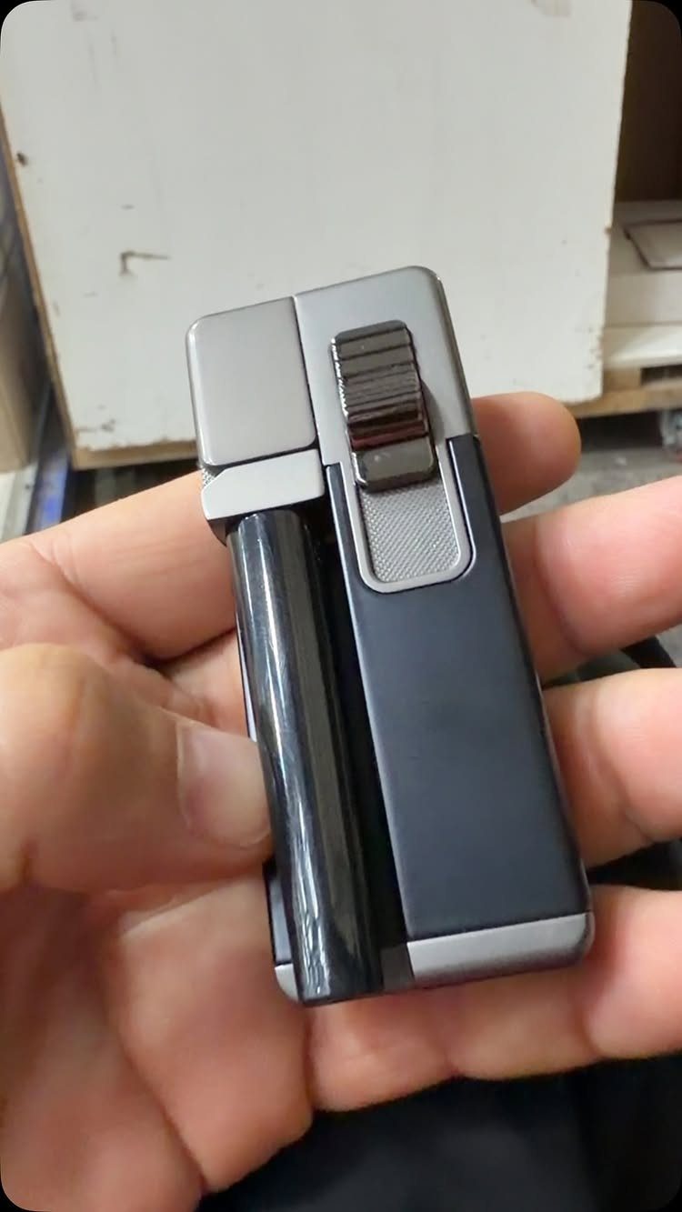 Sleek black and silver metal lighter held in a person's hand.