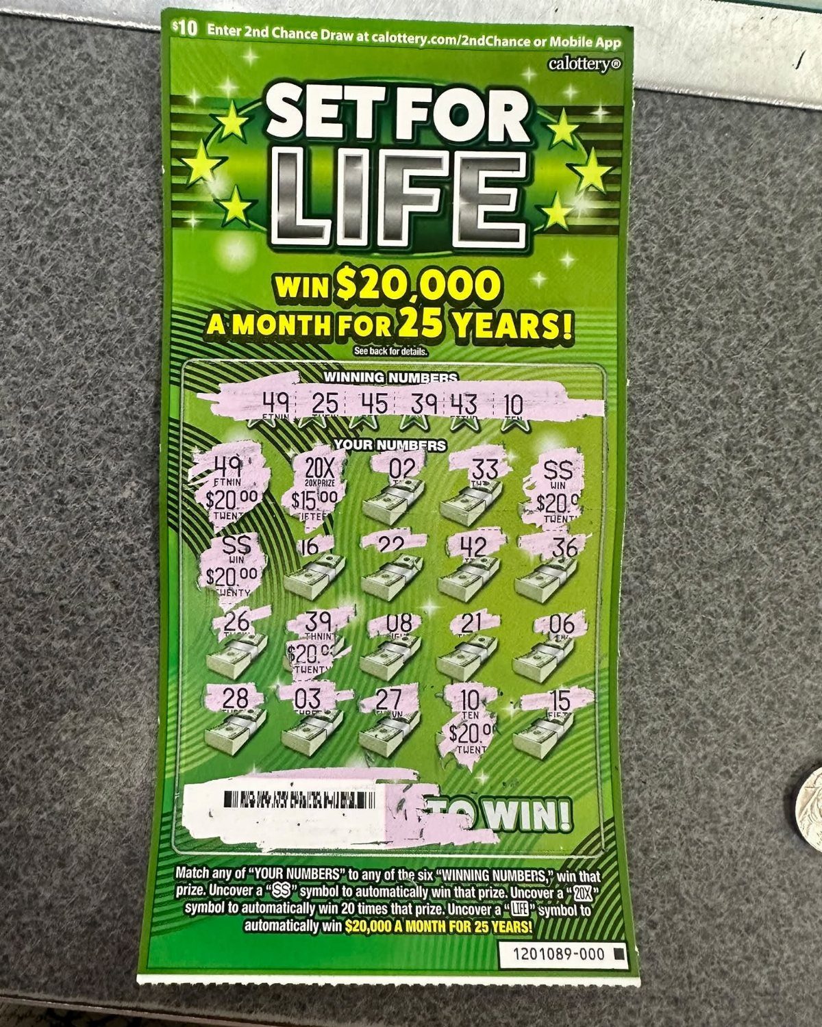 Set for Life scratch-off lottery ticket with revealed numbers on a grey background