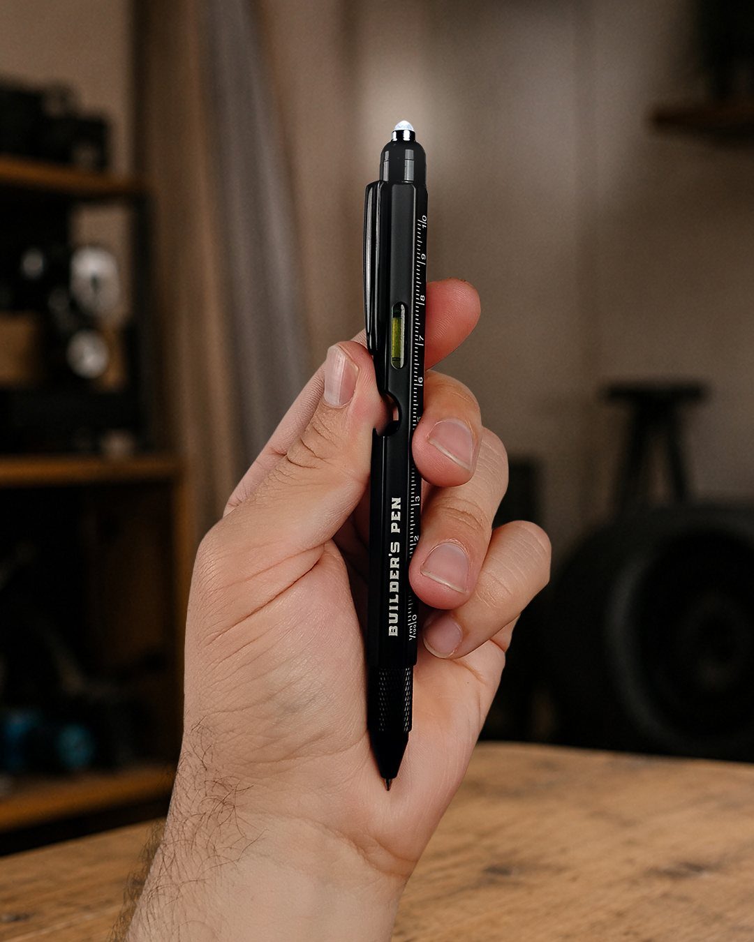 Black builder's pen with ruler markings held in a person's hand.