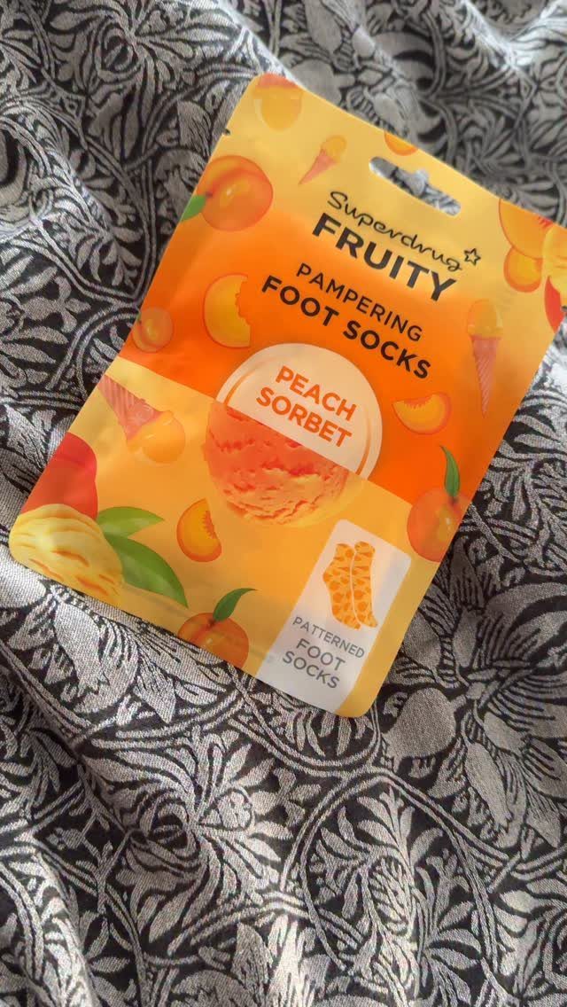 Peach sorbet pampering foot socks in packaging on patterned fabric background