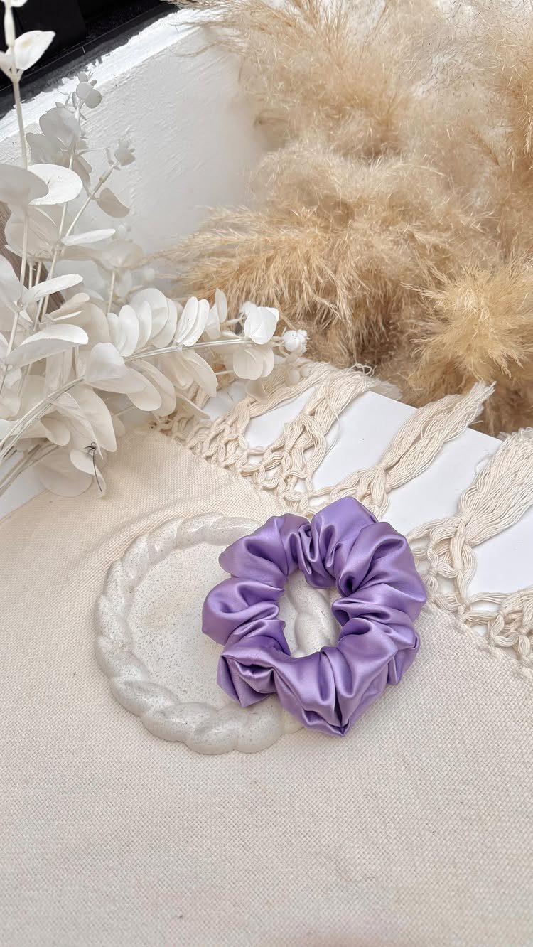 Purple satin scrunchie on a white scalloped dish with pampas grass background