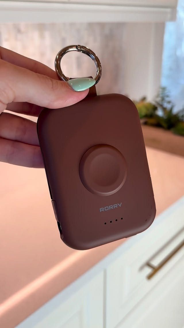 Brown portable power bank with a keychain held by a hand.