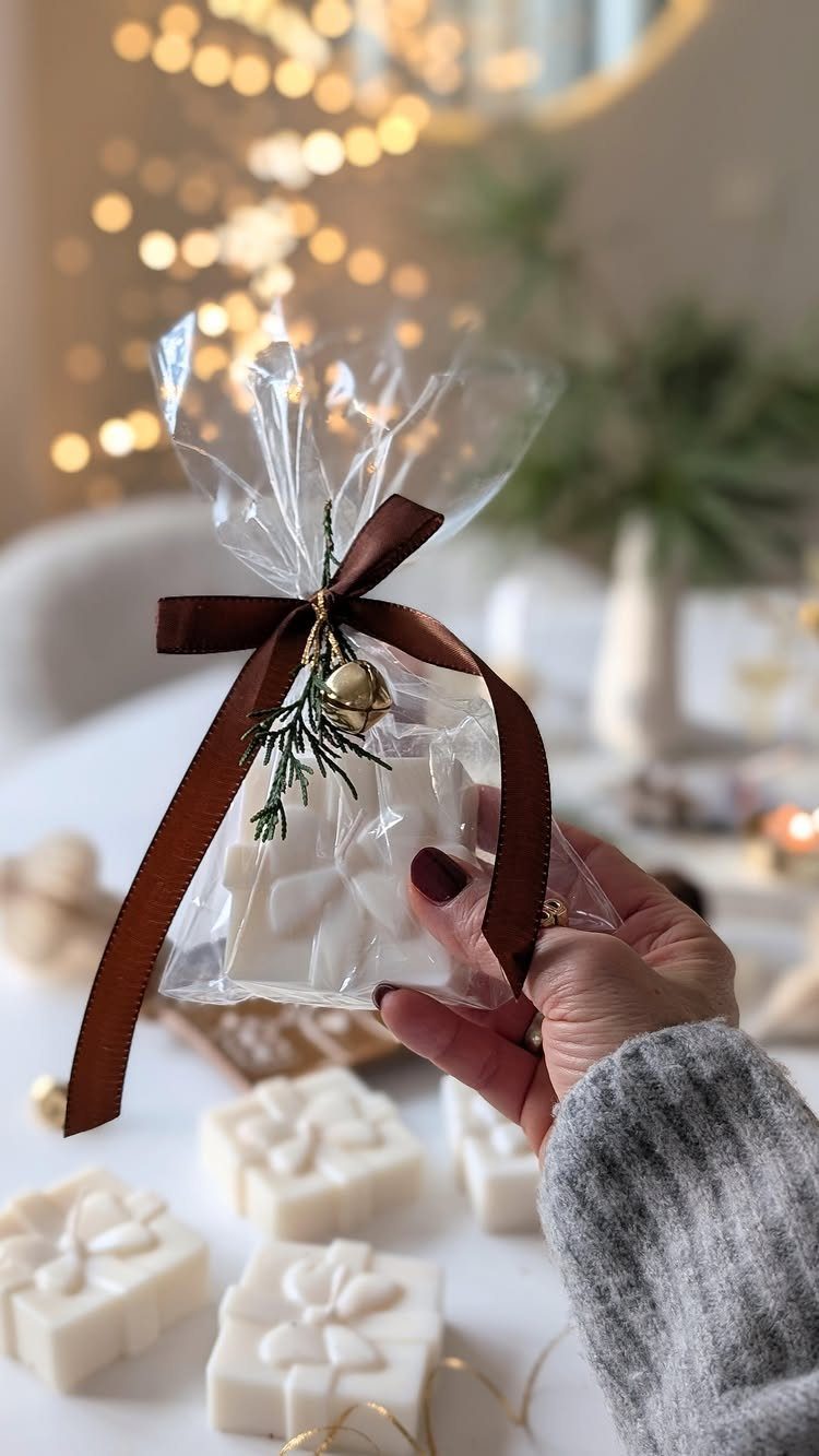 White square candles with bow designs in a clear gift bag with ribbon.