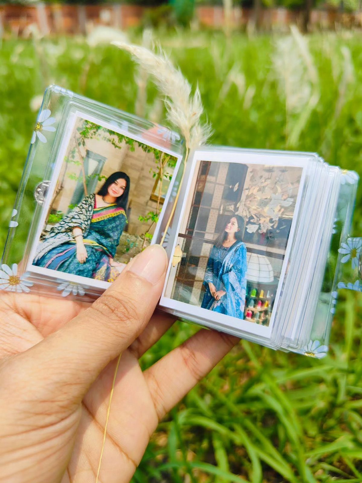 Small clear photo album with daisy decorations showing photos of a woman.