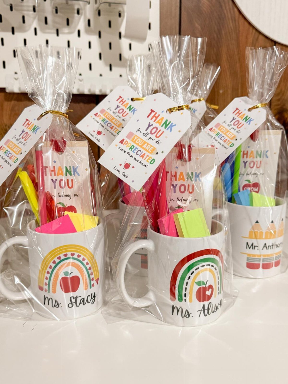 Teacher gift mugs with rainbows and apples filled with stationery and wrapped in cellophane