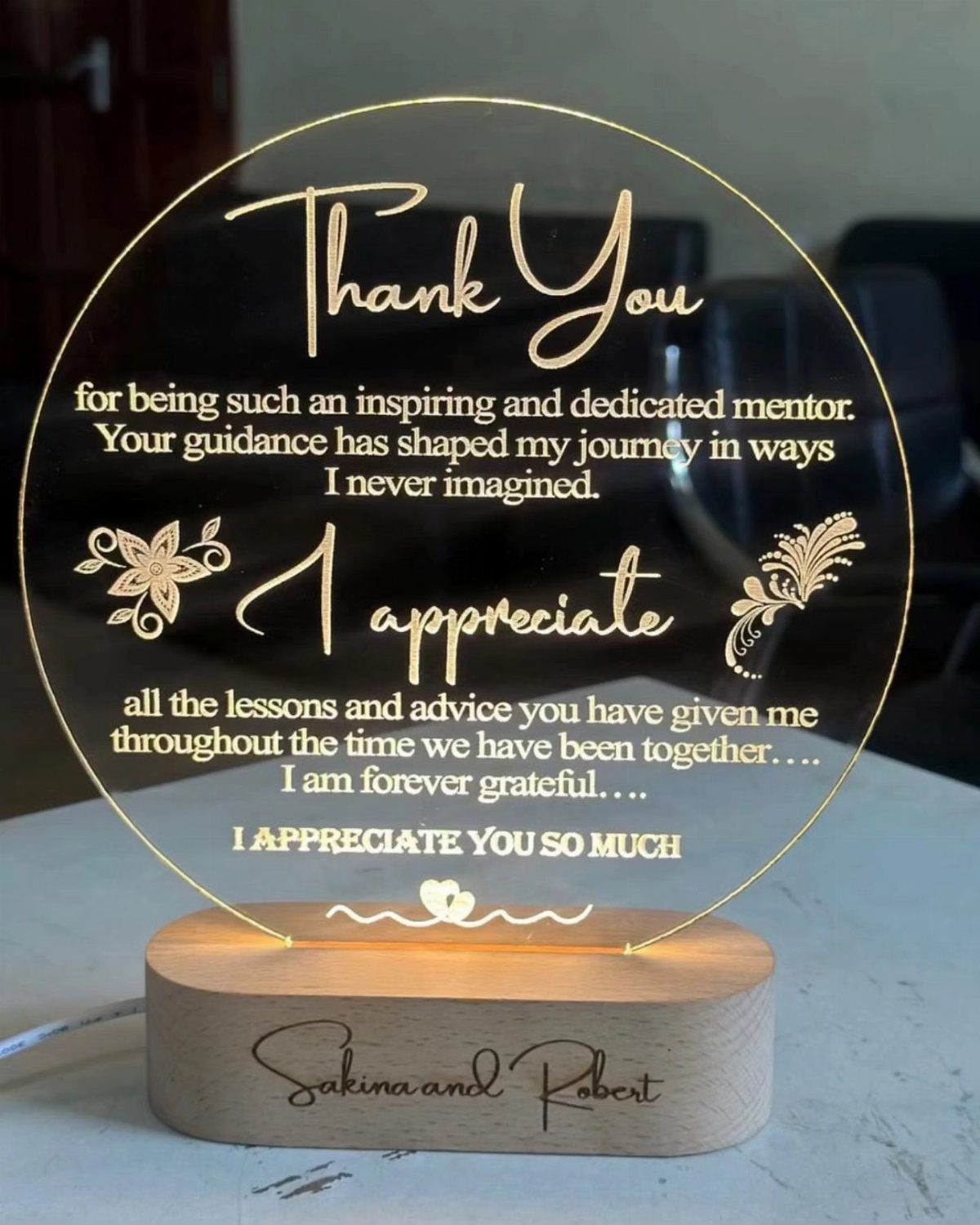 Circular acrylic thank you plaque with gold text on a wooden base