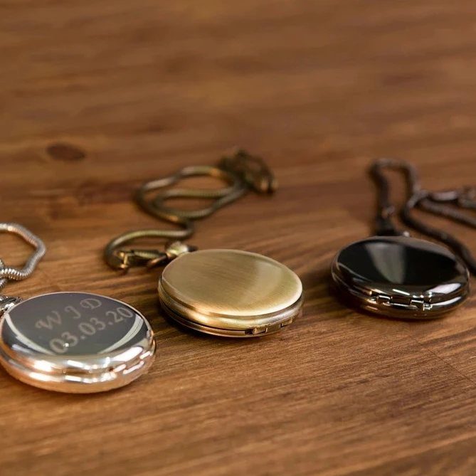 Three metal lockets in silver, gold, and black on a wooden table