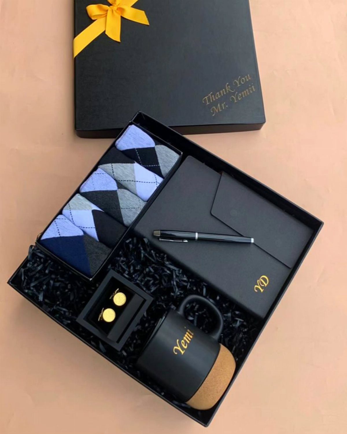 Black gift box with a mug, pen, notebook, and ties for a man.