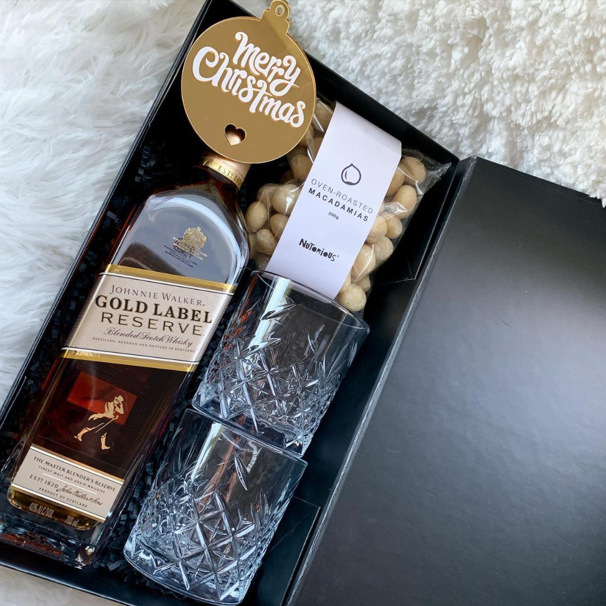 Whiskey gift set with Johnnie Walker bottle, crystal glasses, and macadamia nuts.