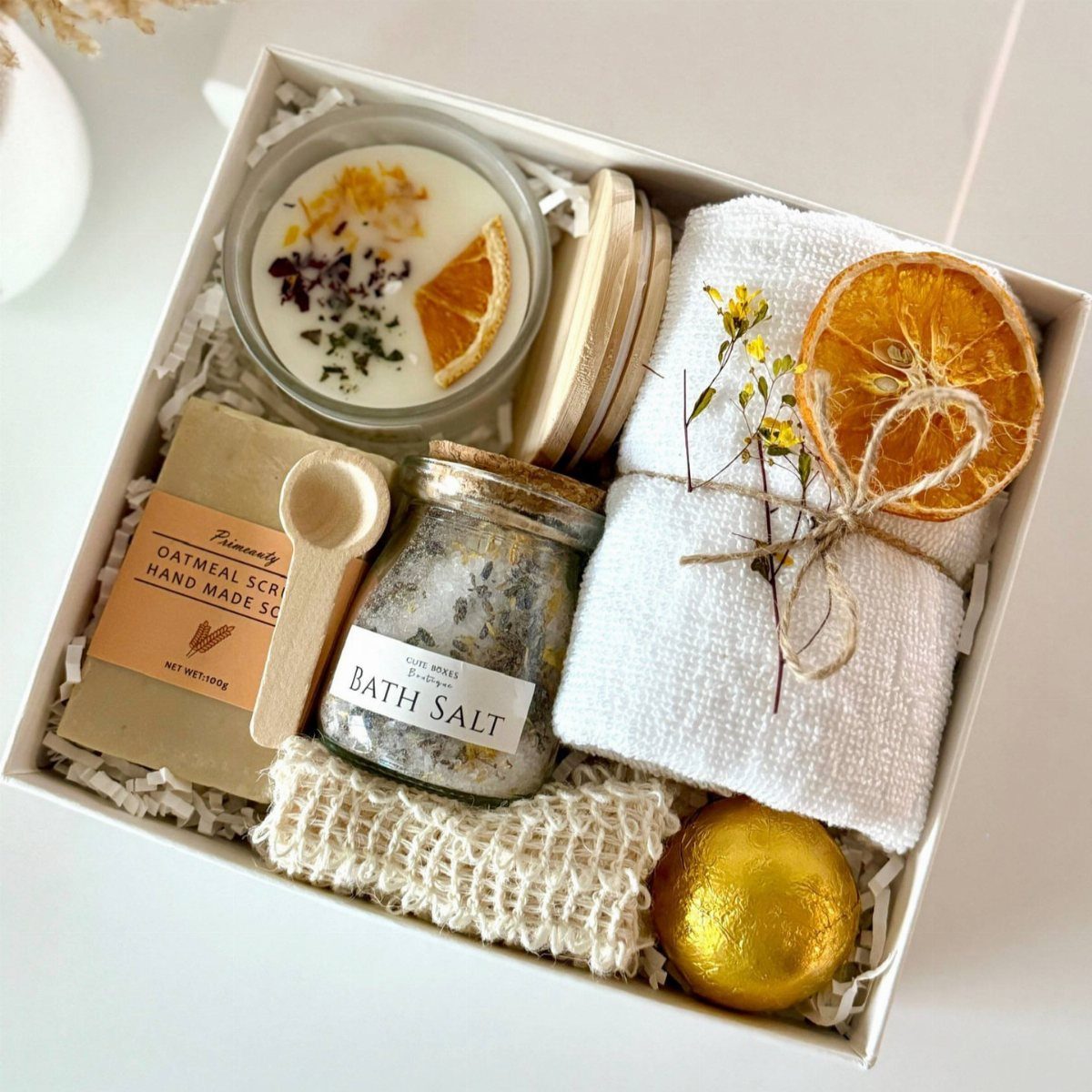 Bath gift set with bath salts, oatmeal scrub, candle, towel, and gold bath bomb.
