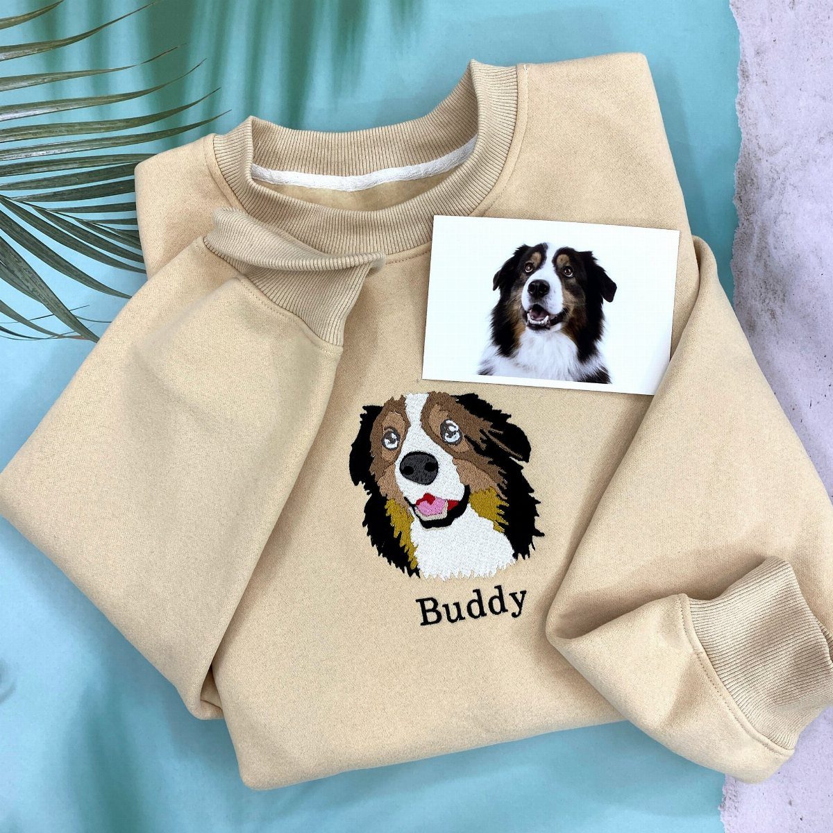 Beige sweatshirt with an embroidered dog portrait and name Buddy next to a photo