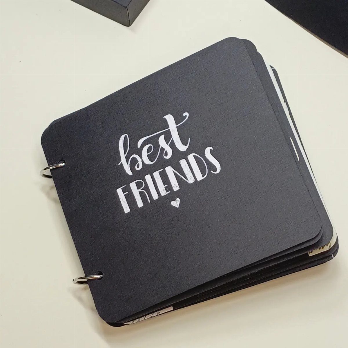 Black ring-bound journal with white best friends lettering on the cover