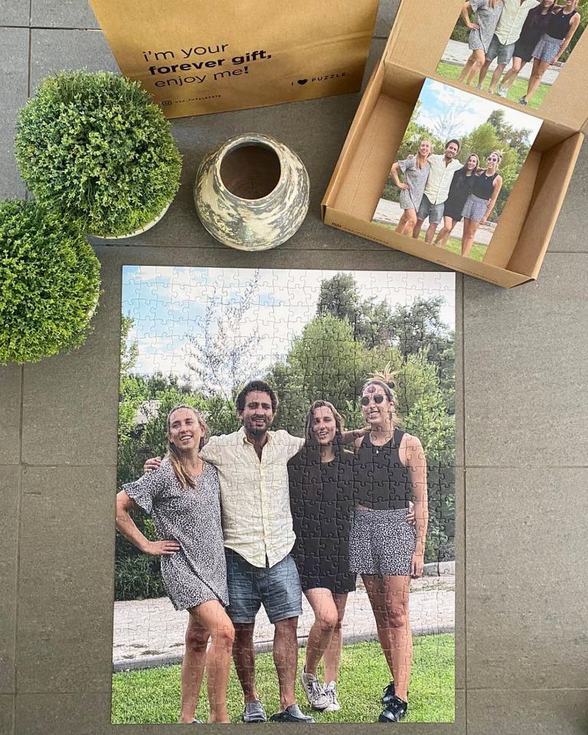 Completed custom jigsaw puzzle of four friends next to its cardboard packaging.