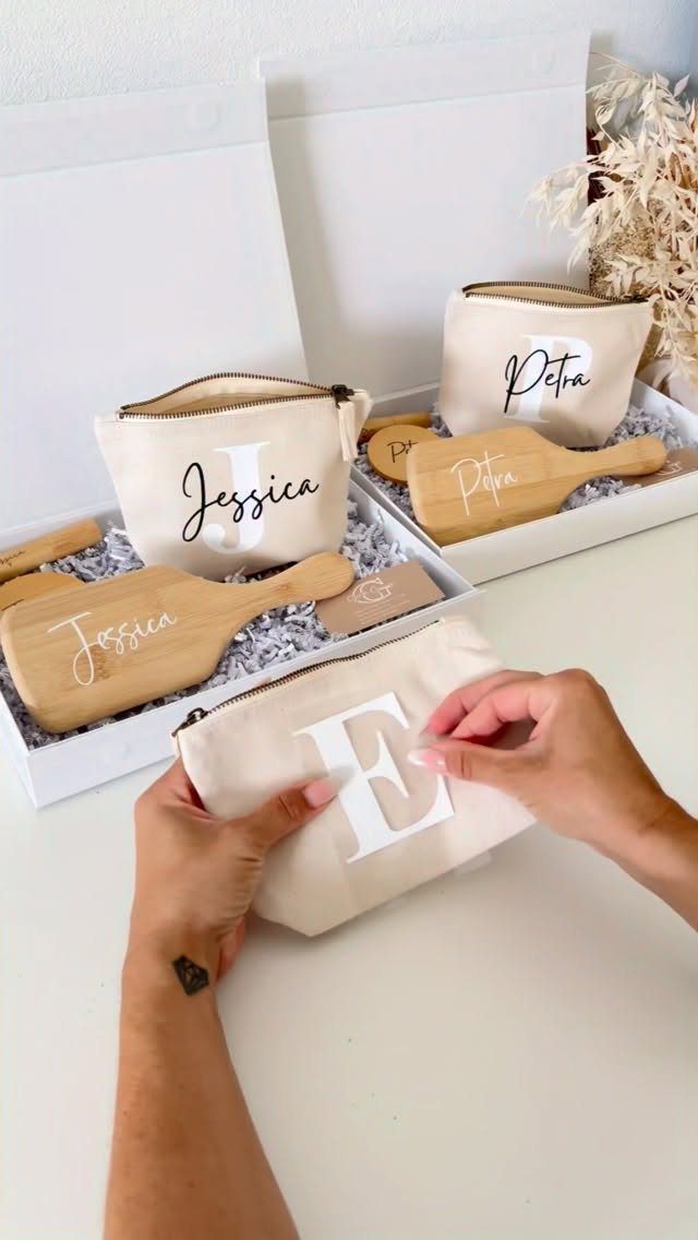 Personalized beige canvas pouches and wooden spatulas inside white gift boxes.