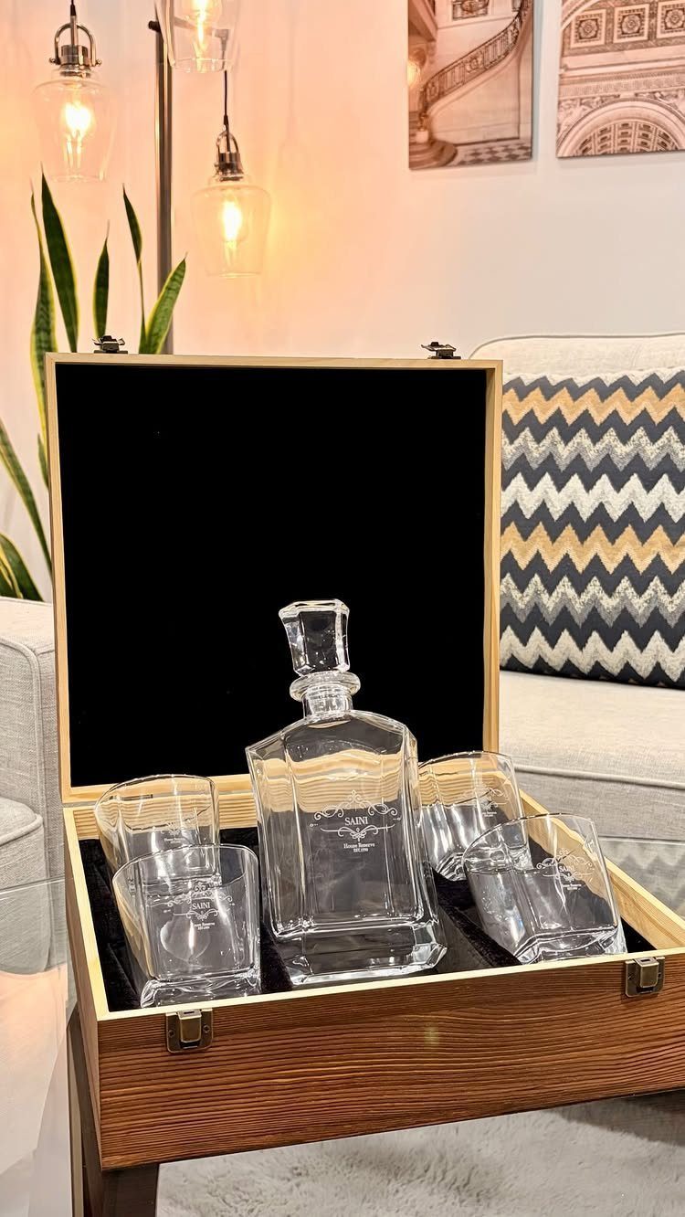 Glass decanter and four tumblers inside a wooden gift box in a living room.