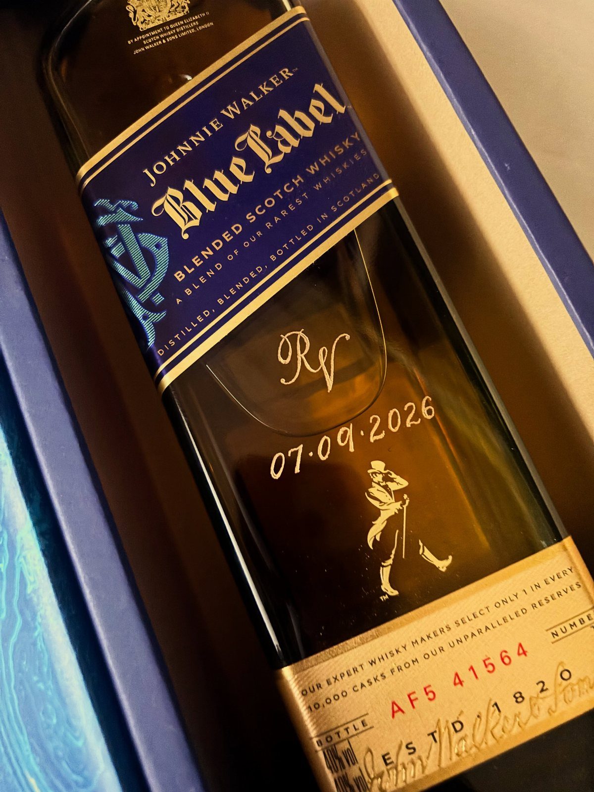 Engraved Johnnie Walker Blue Label whiskey bottle with gold initials and a date.
