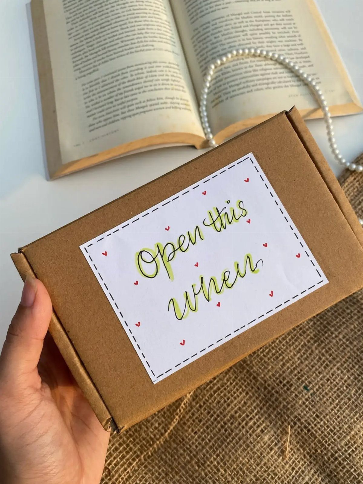 Brown gift box with Open this when label held over an open book