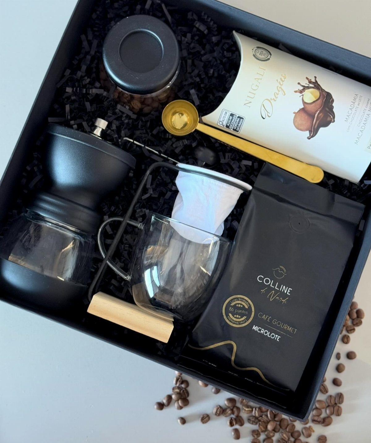 Coffee gift set in a black box with grinder, beans, and glass mug.