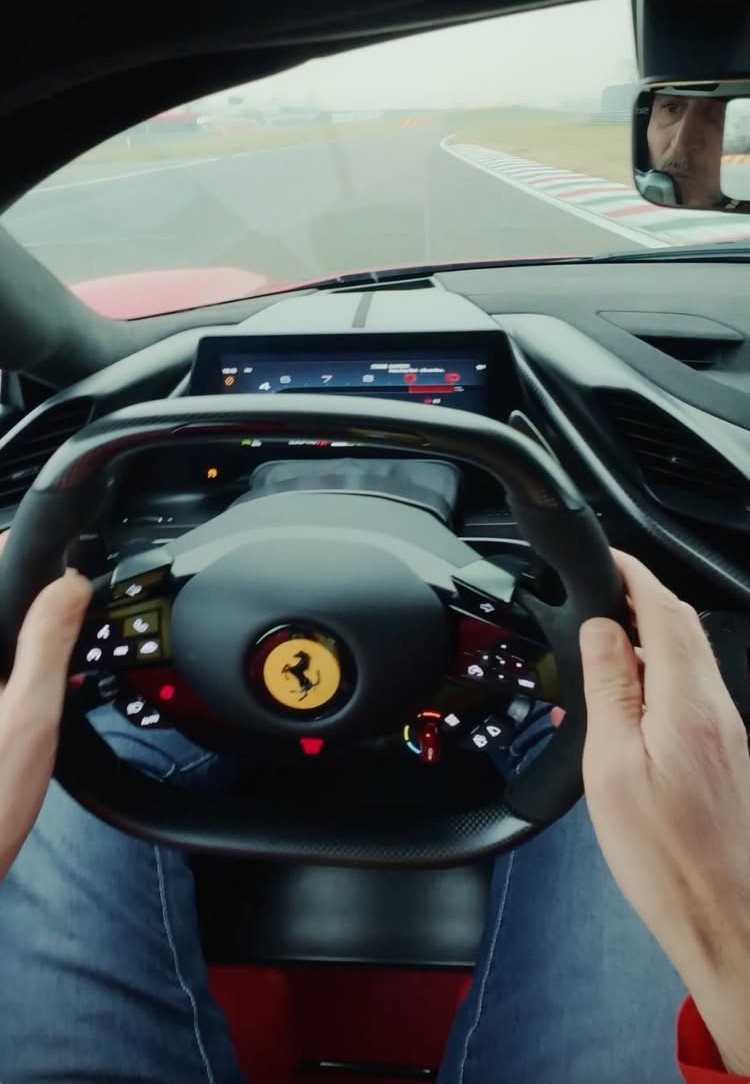 First-person view of a person driving a Ferrari race car on a track