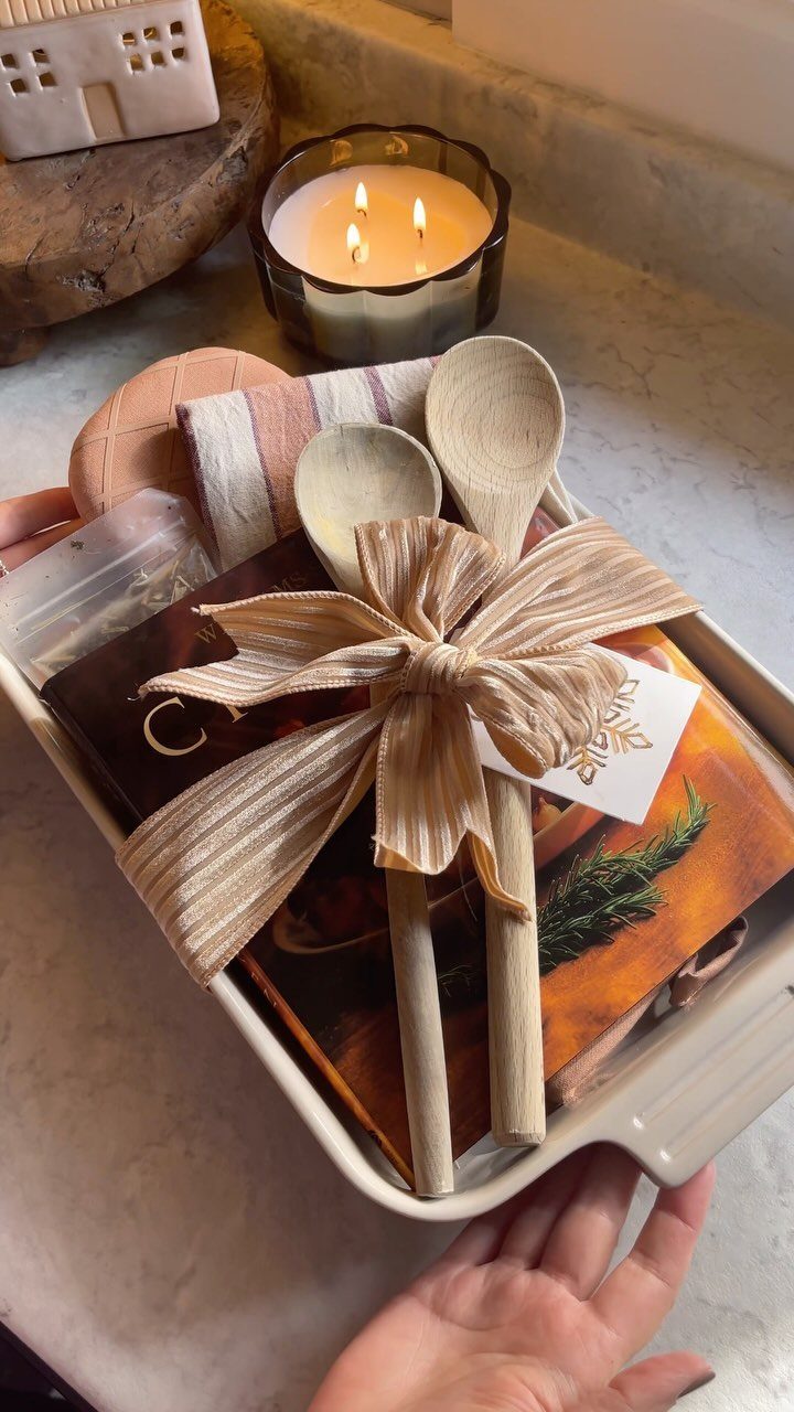 Cookbook and wooden spoons tied with a ribbon in a white gift tray