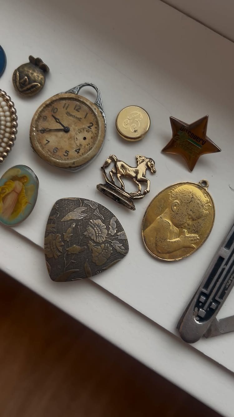 Vintage jewelry collection featuring a small clock, gold horse brooch, and oval locket.