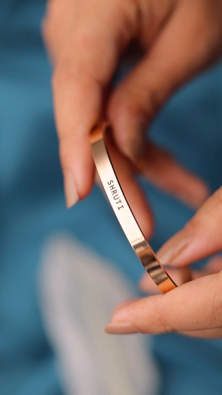 Gold cuff bracelet with the name SHRUTI engraved on the inner band.