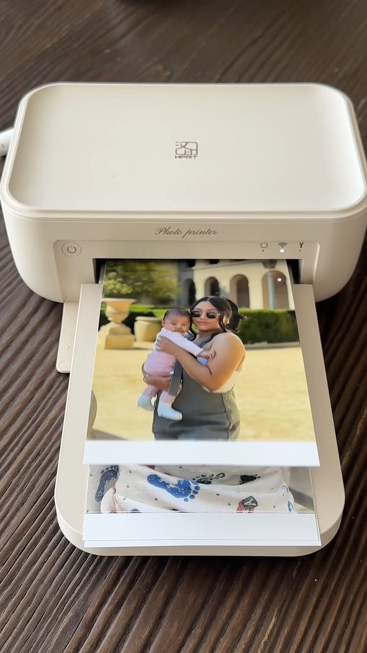 White portable photo printer printing a picture of a woman holding a baby.