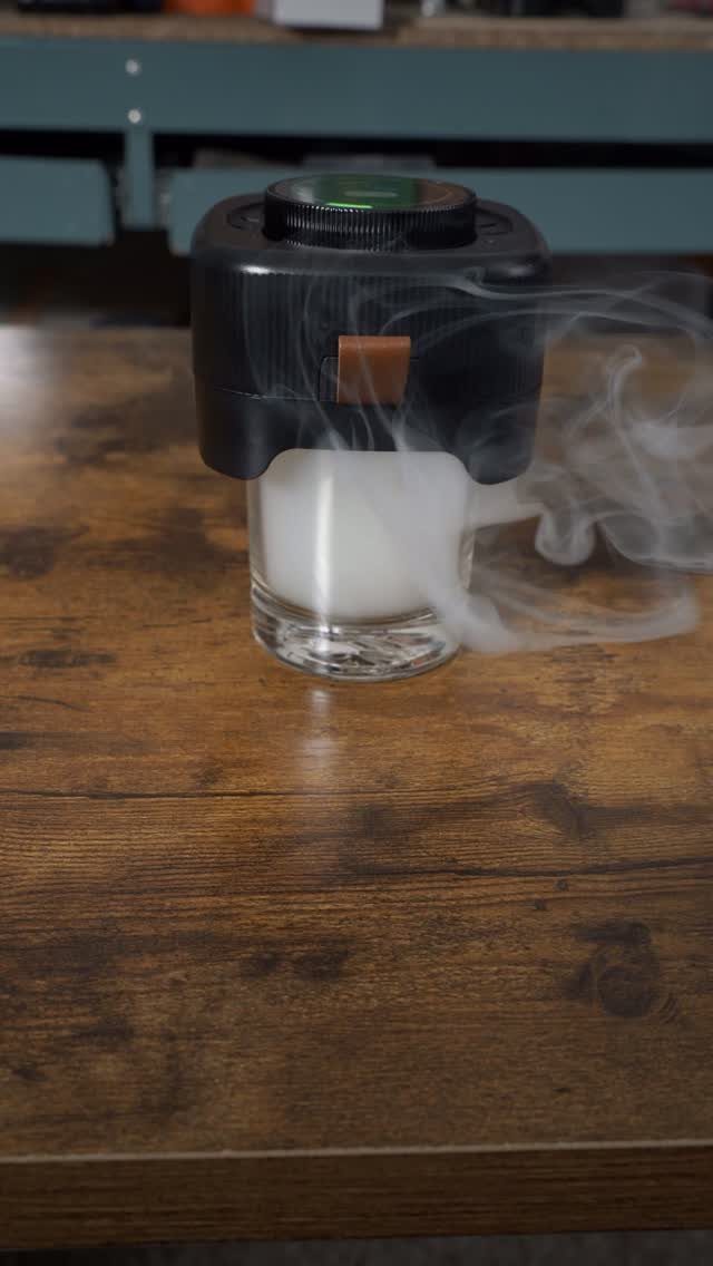 Cocktail smoker device on a glass filled with smoke on a wooden table
