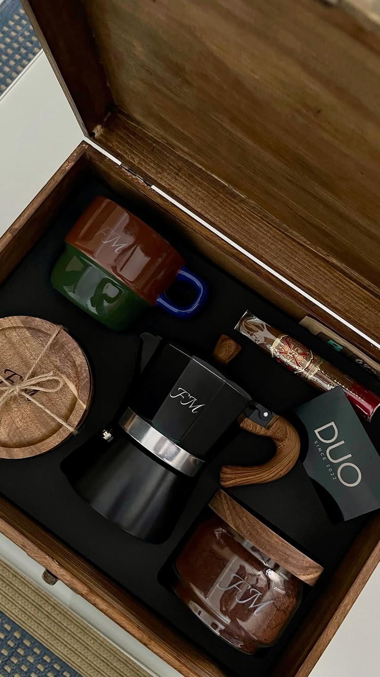 Wooden gift box containing a Moka pot, colorful mugs, and coffee treats.