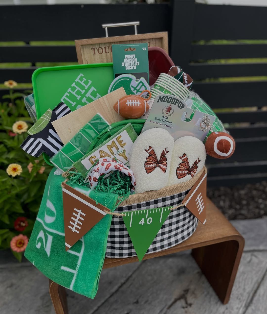 Football-themed gift basket with slippers, towels, and mini footballs in a checkered bin.