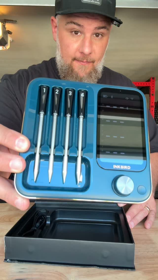 Wireless meat thermometer kit with four probes held by a man in a workshop.