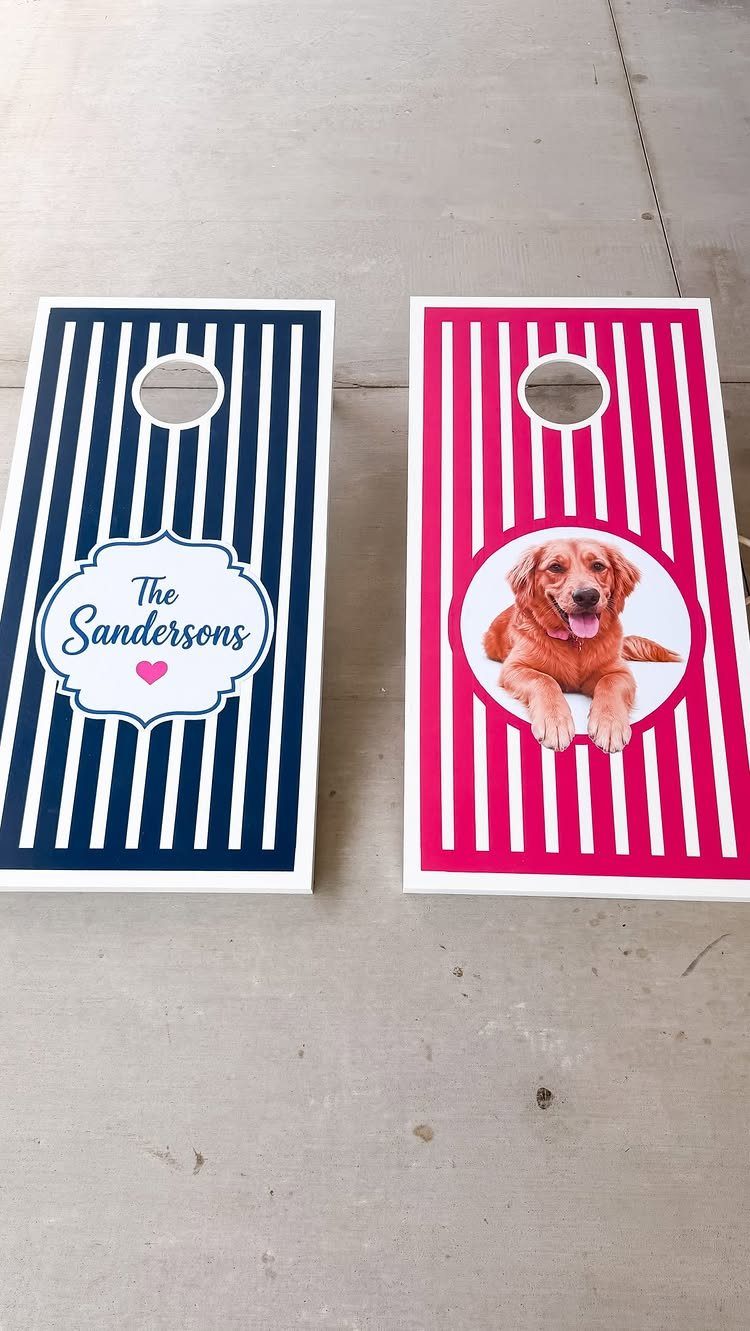 Two personalized cornhole boards with stripes, one featuring a family name and one a dog.