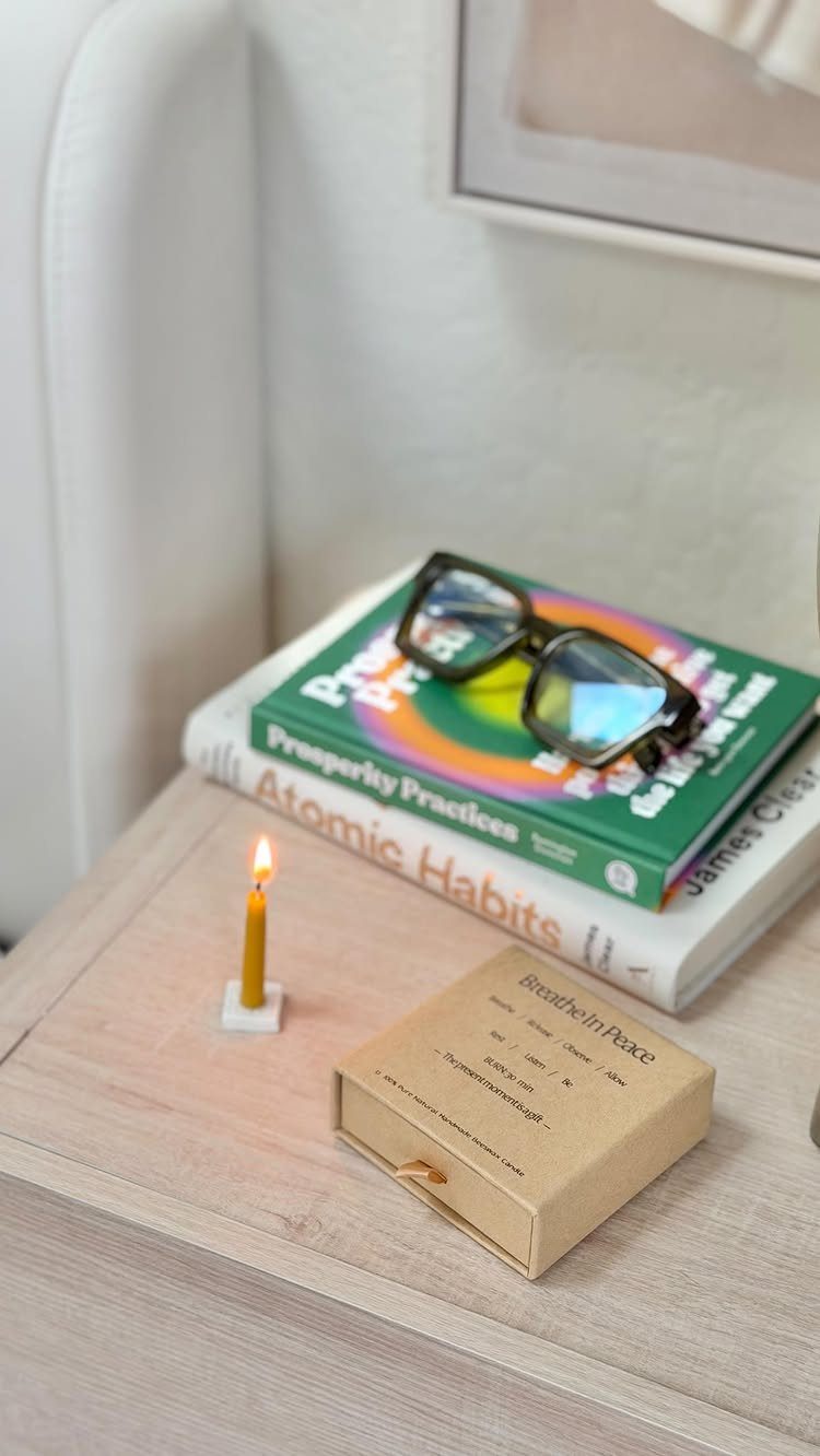 Wellness gift set with books, a lit candle, and a wooden box on a table.