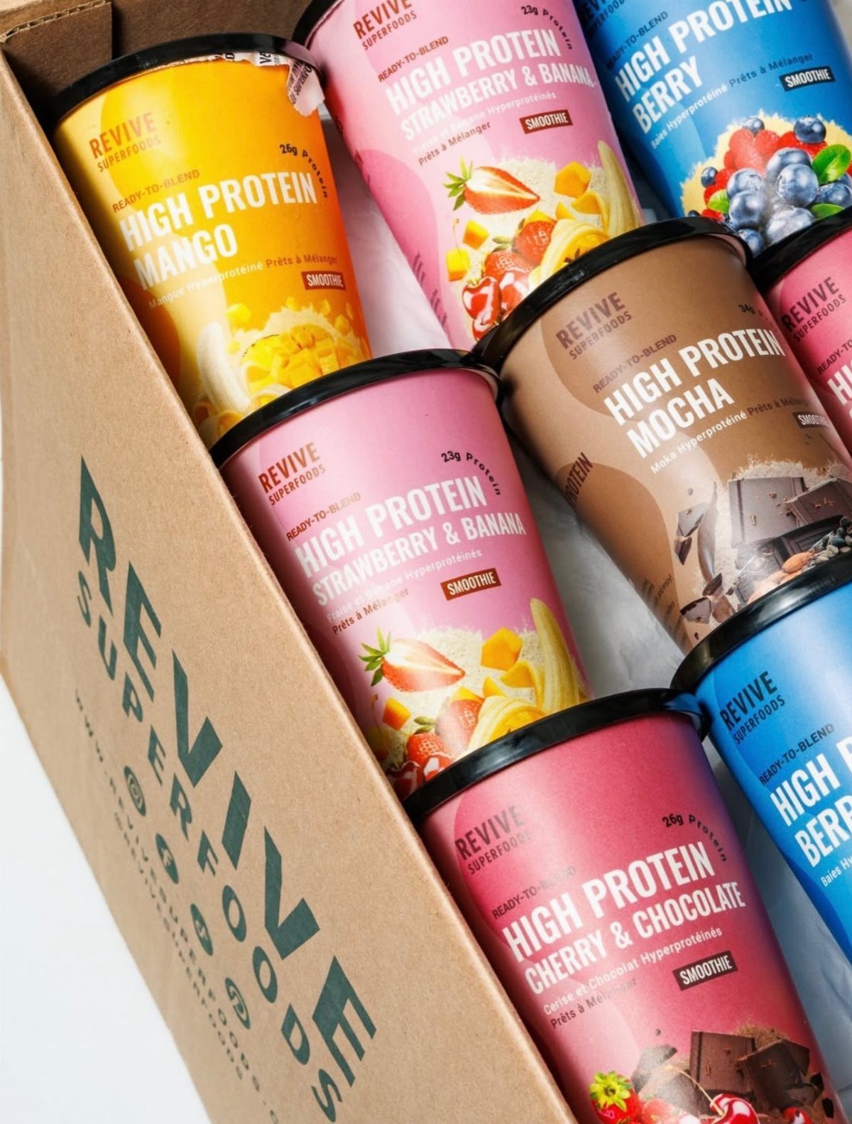 Colorful protein smoothie cans packed inside a cardboard Revive Superfoods delivery box.